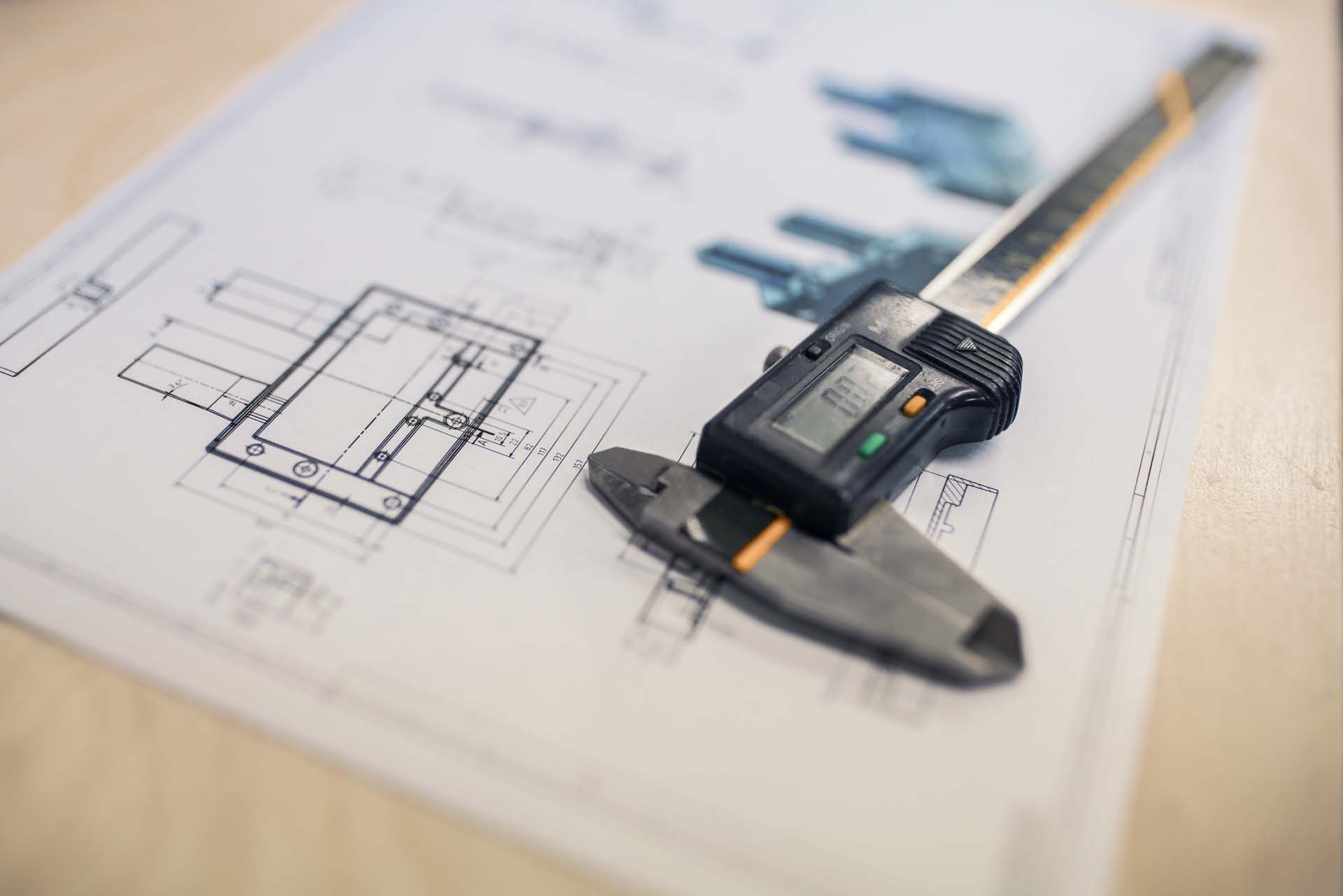 Elektronischer Messschieber liegt auf dem Tisch auf einer Konstruktionszeichnung